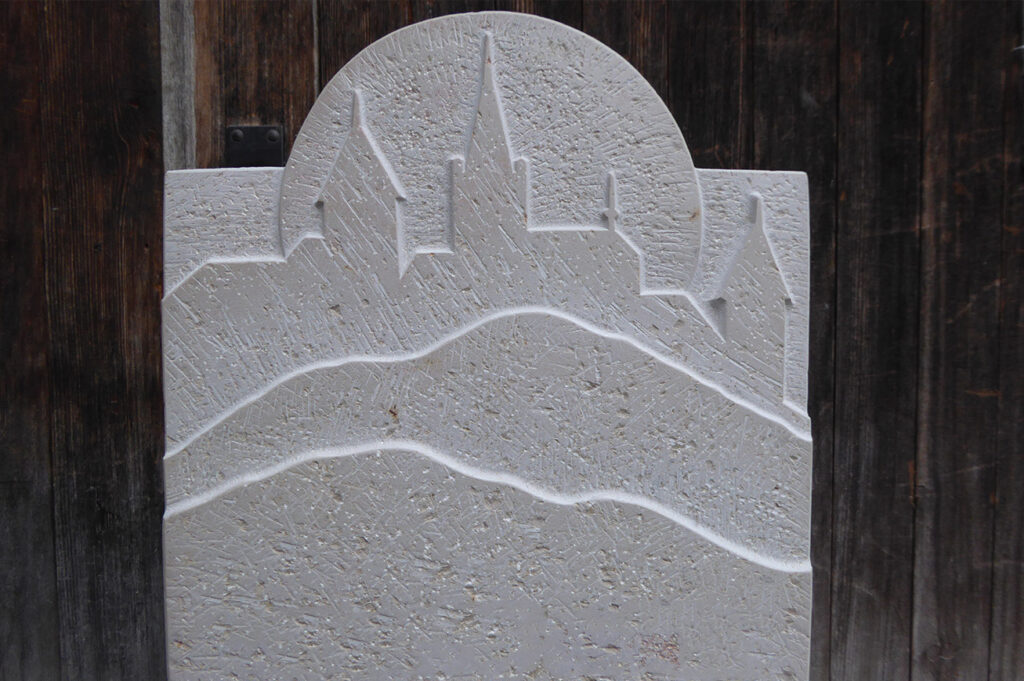 Grabzeichen mit Relief der Skyline einer Stadt mit Kirchtürmen